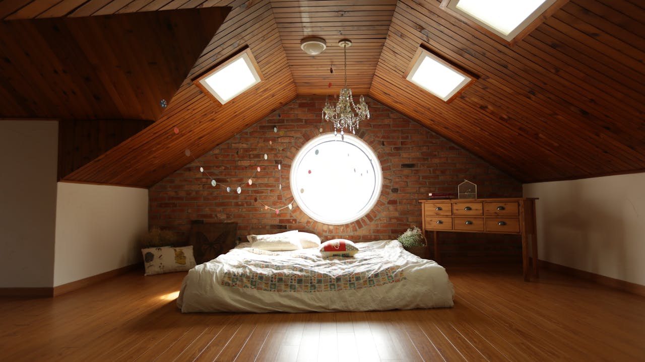 About A warm and inviting attic bedroom featuring a unique brick wall and wooden ceiling design.