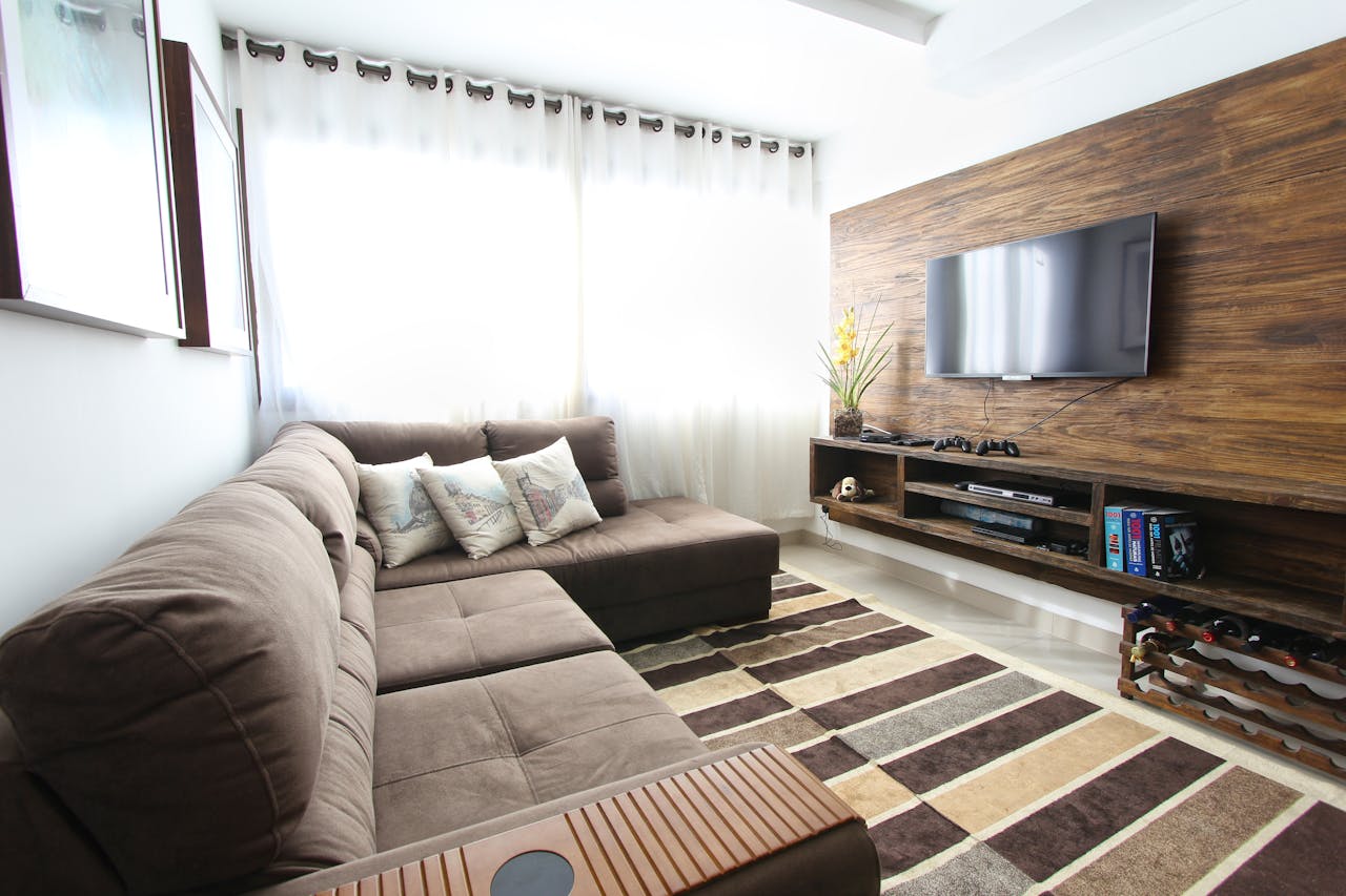 About Stylish modern living room featuring a brown sofa, wall-mounted TV, and interior decor.
